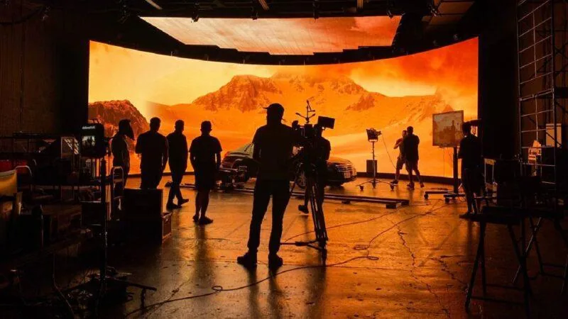 Film crew shooting a car scene against a large LED volume wall on a virtual production stage